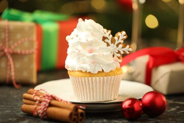 Festive cupcake with cookie, cinnamon and christmas decor on black table, closeup