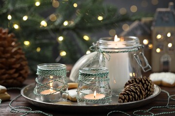 Christmas lanterns, cookies and festive decor on wooden table against background with blurred lights, closeup. Bokeh effect