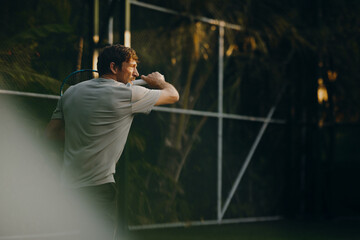 Man practicing tennis backhand on vacation