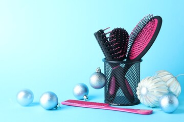 Different hairdresser's tools and Christmas decor on light blue background, closeup. Space for text