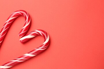 Naklejka premium Heart made of tasty candy canes on red background, flat lay with space for text. Merry Christmas and Happy New Year