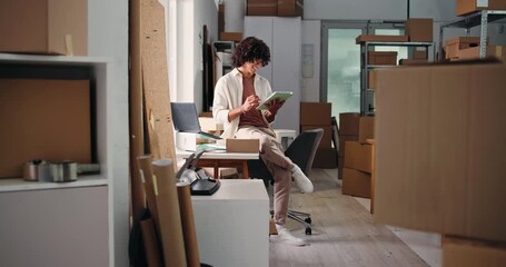 Laptop, logistics and tablet with man in office for delivery, distribution or shipping of boxes. App, computer and planning with employee in supply chain depot for agenda, parcel tracking or schedule