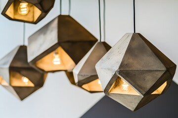 A collection of stylish geometric pendant lights made of concrete, each beautifully illuminating the space with a unique artistic flair, perfect for modern interior design.