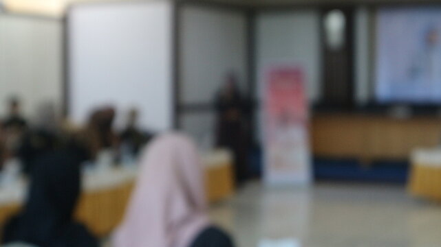 Several people gathered in a hall to attend a seminar in a blurry photo