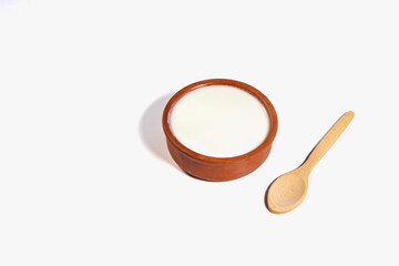 Homemade plain yogurt and wooden spoon in a clay bowl on a white background