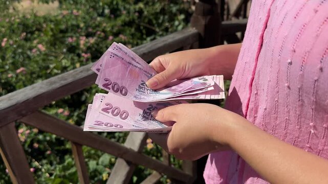 Female tourist counting 200-lira notes on Turkish resort, inflation concept