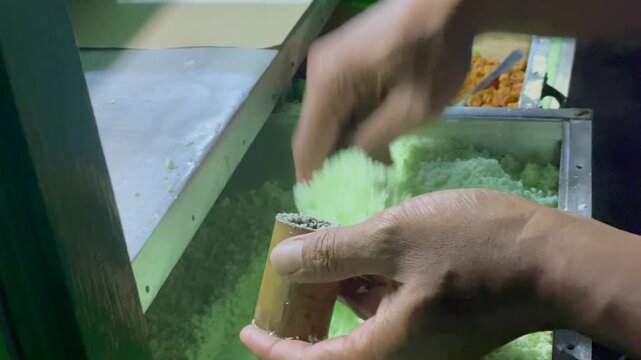 Traditional indonesian putu cake preparation &ndash; filling coconut mixture into bamboo mold.