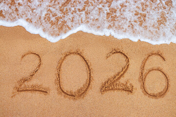 Happy New Year 2026 concept, lettering on the beach. Written text on the sea beach at sunrise.