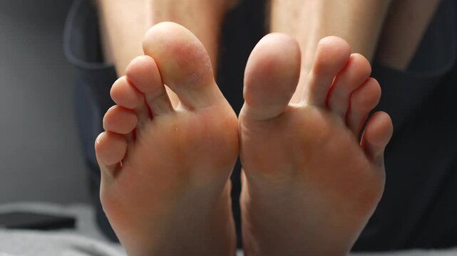 A close-up of a man's heels.
A barefoot man sits on a jivan.
A man wiggles his toes.
Toes, foot, leg, body, skin, barefoot