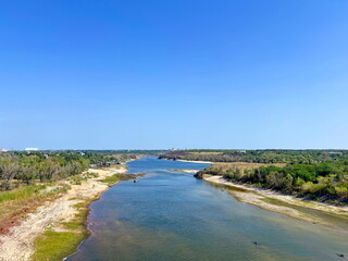 A bird's-eye view of the calm blue water surface of the Dnieper River, which has exposed its sandy banks after a dry summer.