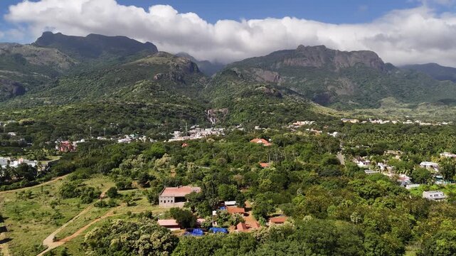 Aerial view of Courtallam nestled in the Western Ghats, showcasing lush forests, cascading waterfalls, and colorful townscapes surrounded by tropical greenery.