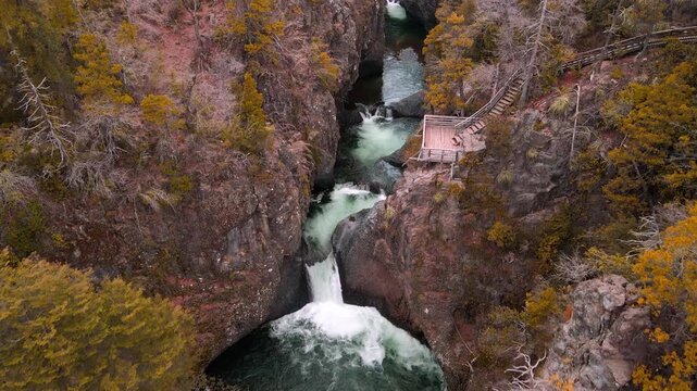 Tilting down drone aerial of waterfalls with viewing boardwalk, Siete Tazas National Park, &Ntilde;uble, Chile with emerald pools and autumn forest