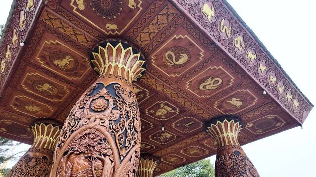 Intricately carved wooden pavilion columns and decorative ceiling patterns at a Thai temple in Chiang Mai.