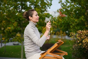 Woman painting outdoors in a park.