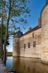 Side view of Château de Lavaux-Sainte-Anne with its historic stone walls and tower rising above the reflective moat on a sunny day captures the tranquil charm of this iconic Belgian castle in the coun
