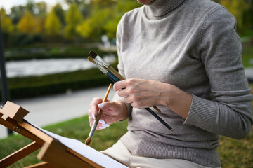 Close-up of artist hands holding painting brushes.