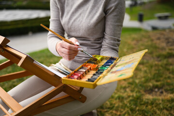Close-up of artist mixing colors on watercolor palette.
