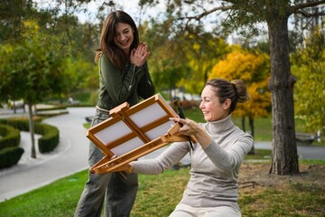 Artist showing finished portrait to smiling model outdoors
