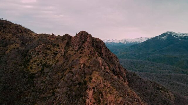 Backward drone aerial of rugged mountain ridge at sunset, &Ntilde;uble Region, Chile with snow-capped Andes peaks and dramatic twilight sky