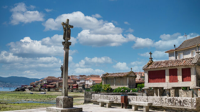 Cruz de piedra y tradicionales h&oacute;rreos gallegos en la hermosa villa medieval de Combarro, Espa&ntilde;a. Con cielo editado