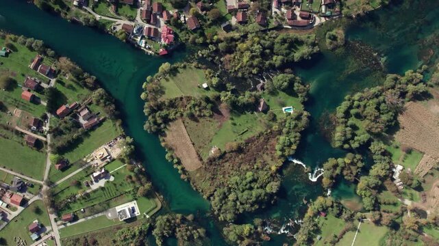 Aerial top view of the Una River forming a natural heart shape surrounded by green forest and rural landscape near Bihac, Bosnia and Herzegovina. Clear turquoise water seen from above.