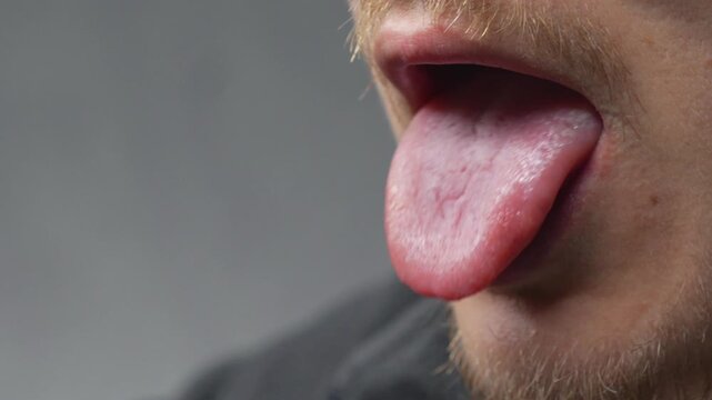 A close-up of a person sticking their tongue out of their mouth.
Facial expressions and body parts.
A healthy person's tongue is free of plaque and germs.
Close-up of the oral cavity.
Tongue, showing,
