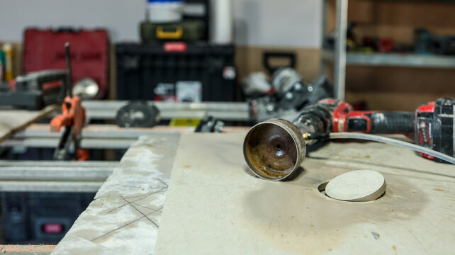 Close-up of a drill bit and a hole saw on a workbench in a workshop