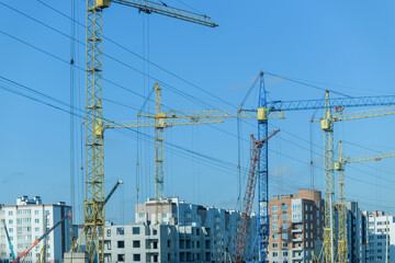 Construction cranes working on a new residential building under a clear blue sky