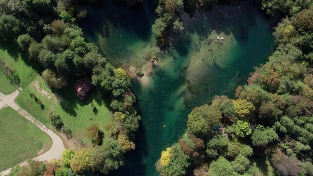 Drone footage of the Una River forming a perfect heart shape near Bihac japodski otoci, Bosnia and Herzegovina. Turquoise water and dense green forest seen from above, symbolizing love and nature.