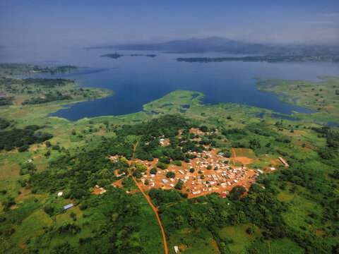 Aerial view of a tapestry of green foliage meets the tranquil blue waters of a vast lake, Tepo, Oti Region, Ghana.