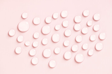 Water drops on pink background. Cosmetic liquid
