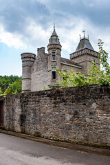 Spontin Castle Château De Spontin rises beyond its tall stone wall, showcasing pointed towers and ornate turrets under a dramatic cloudy sky in the Belgian countryside, rich with medieval heritage and