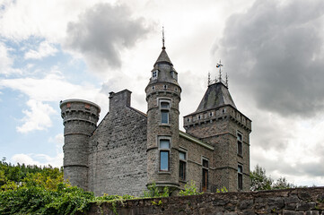 Imposing towers and intricate stonework of Spontin Castle rise beneath dramatic clouds, showcasing the architectural grandeur and historical essence of one of Belgium’s most enchanting medieval castle