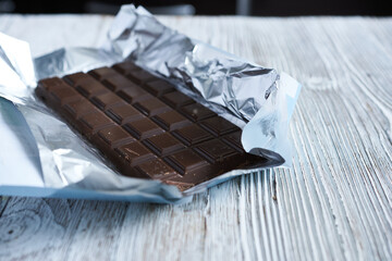 chocolate bar in foil on a wooden background. selective focus.