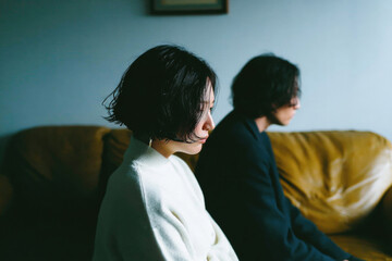 Emotional Distance: Young Asian Couple Sitting Apart on Sofa