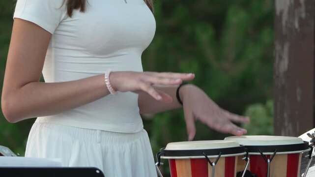 Bongos, playing, music: young woman performs percussion outdoors