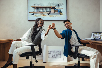 Close-up of two architects sharing a celebratory moment in a design studio