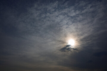 A cloudy sky with a sun shining through the clouds