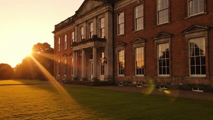 Sunlit brick manor with tall columns and symmetrical windows overlooks a manicured lawn; warm light and long shadows grace the facade, creating a timeless academic atmosphere - georgian home