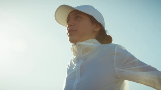 A determined runner takes a moment to prepare for an urban marathon. She wears athletic gear and faces the challenges ahead with strength and focus, embodying fitness and sport.
