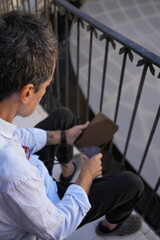 Man kneeling using digital tablet on stairs © JavierBallesterLegua