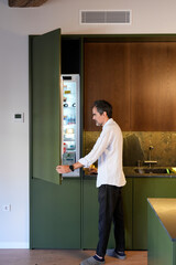 Man opening built in refrigerator in modern kitchen