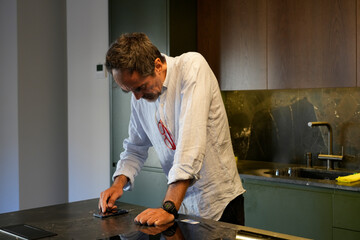 Man cleaning smartphone screen on kitchen counter