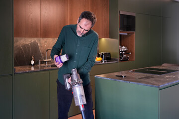 Man cleaning vacuum cleaner filter at home kitchen