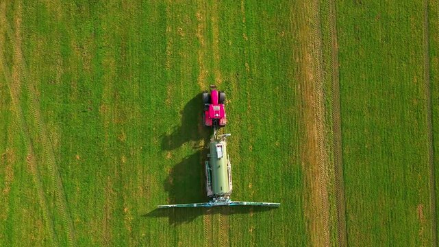 Aerial view of a vibrant pink tractor contrasting against the lush green field, creating a beautiful scene, Andechs, Bayern, Germany.