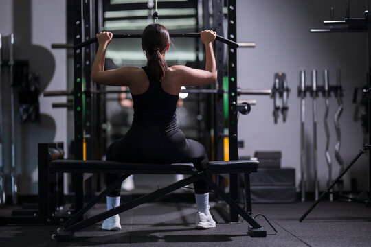 Strong woman lifting weights in a gym during evening workout session for fitness improvement and strength training