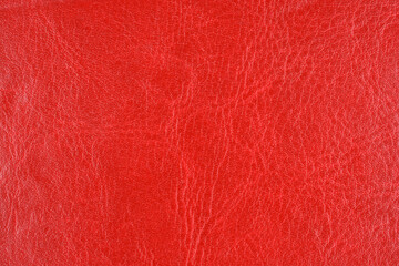 A full-frame, close-up abstract background of a vibrant, deep red faux or genuine leather material with visible wrinkles and a subtle texture