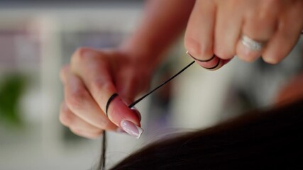 The hairdresser winds a strand of hair around his finger to check the quality of the hair. High quality 4k footage