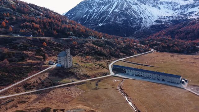 Aerial view of Simplon Hospice, with mountains in the background, exhibiting autumn colors, contrasted against the building's stone, Simplon Hospice, Wallis, Switzerland.