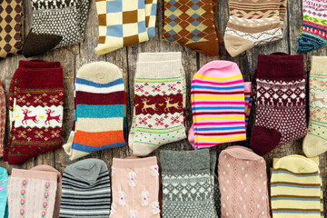 Socks of various colors and sizes are stacked on a textured wooden background. Warm socks for fall and winter. Lots of sock-like clothing.